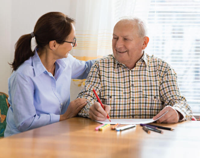 senior man coloring with his caretaker at The Delaney at The Green in Florham Park, NJ