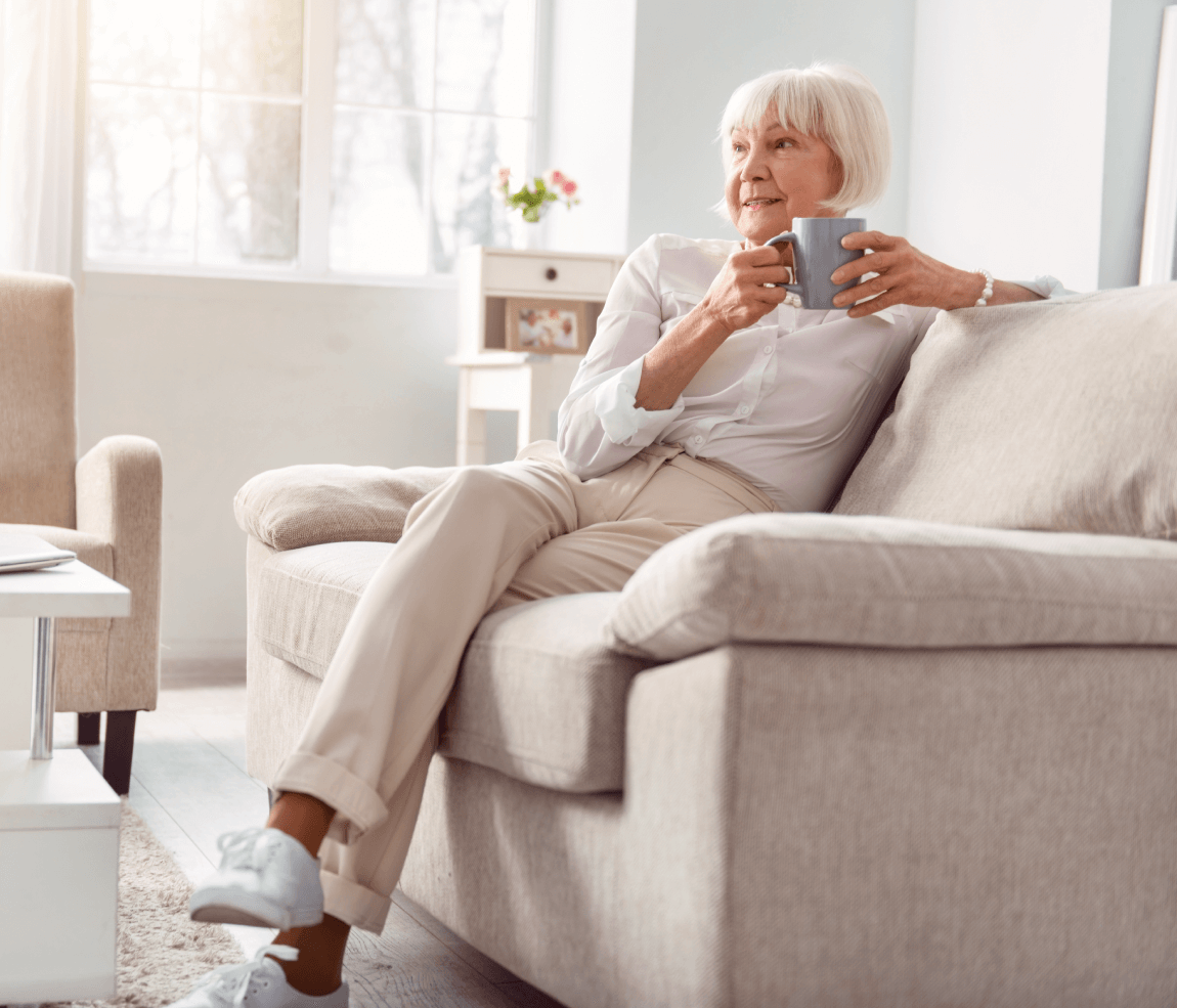Senior woman relaxing on her couch with a cup of coffee