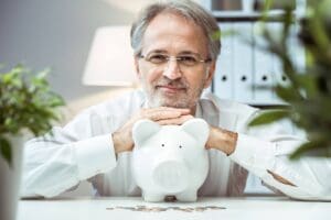 senior man smiling with piggy bank