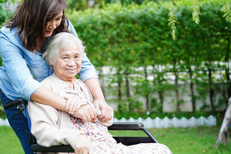 Caregiver help Asian elderly woman disability patient sitting on wheelchair in park, medical concept.