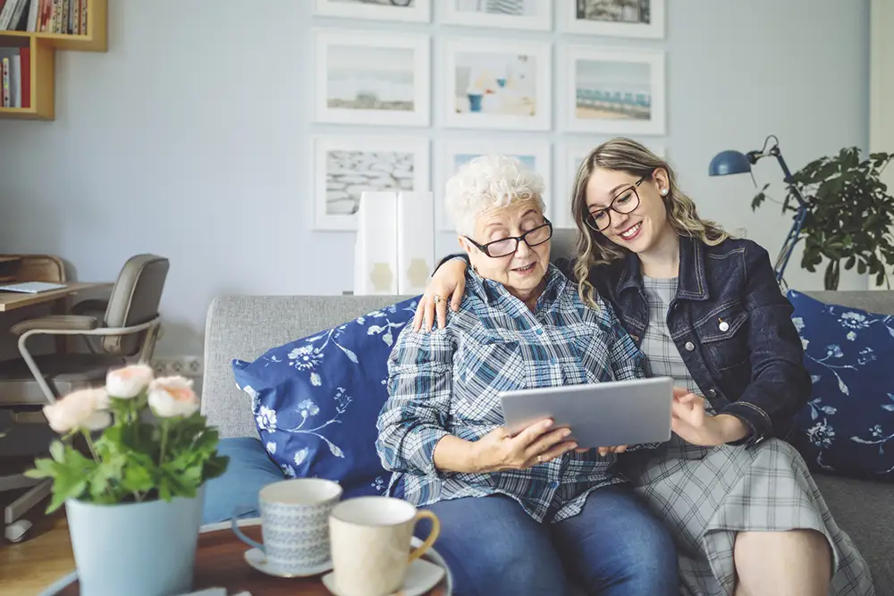 Senior woman at home with daughter looking at an ipad