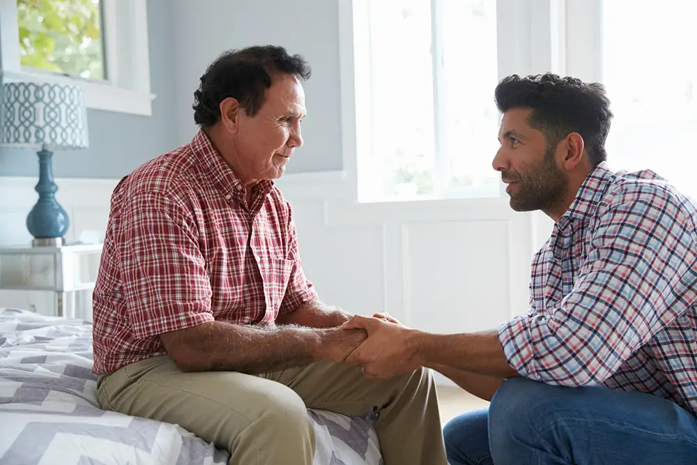 Adult Son Comforting Father Suffering With Dementia