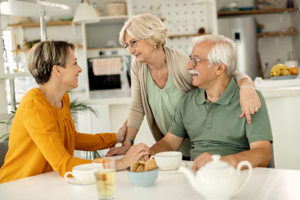 Woman speaks with elderly parents in kitchen