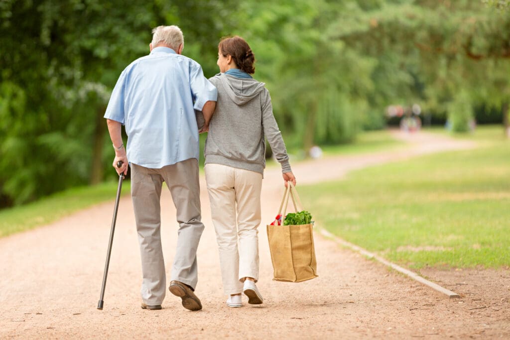Caregiver – woman helping senior man with shopping while moving from assisted living to memory care at The Delaney at The Green.