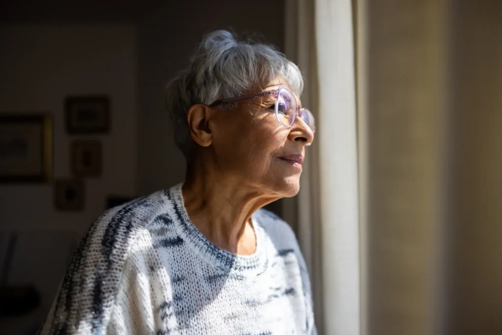 A senior woman looking outside her home while thinking about a memory care checklist.