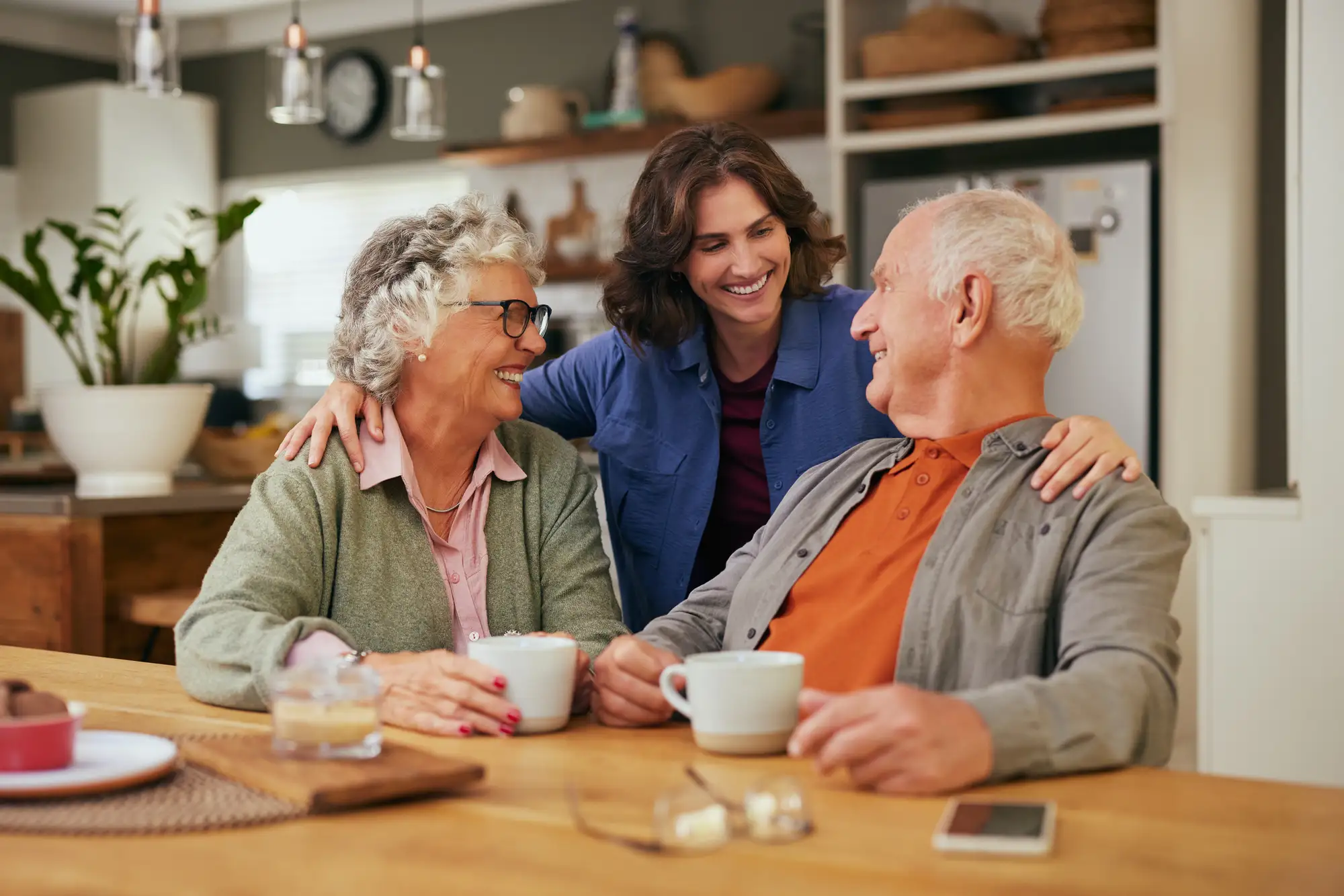 A young adult woman hugging her parents and talking about 35 questions to ask your aging parents at The Delaney At The Green.