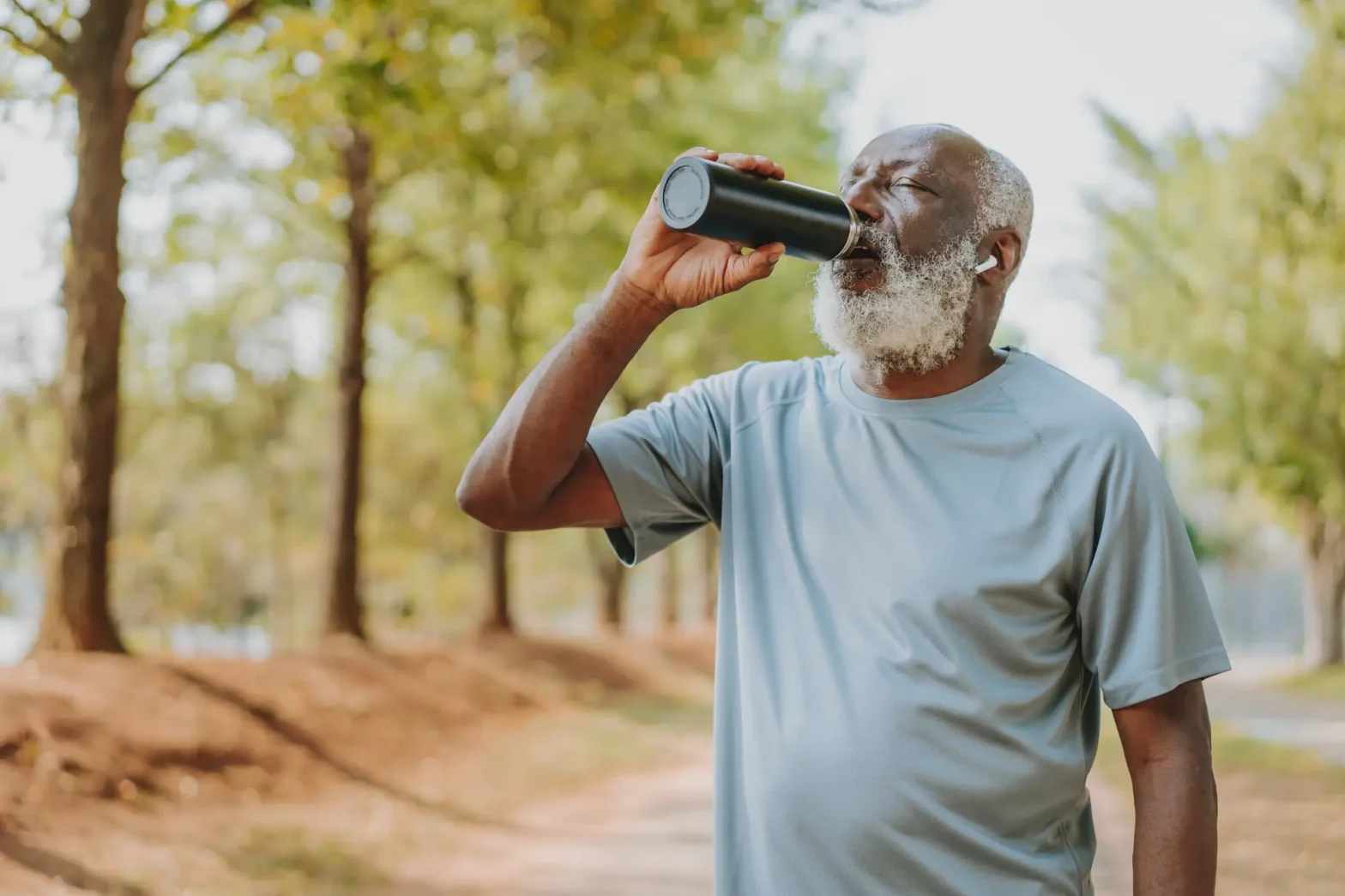 An elderly man enjoying a protein shake from a flask, one of the best energy drinks for seniors.
