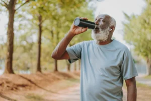 An elderly man enjoying a protein shake from a flask, one of the best energy drinks for seniors.